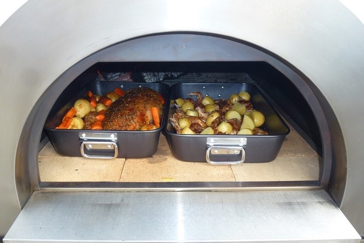 This image shows roast leg of lamb cooking in a woodfired pizza oven