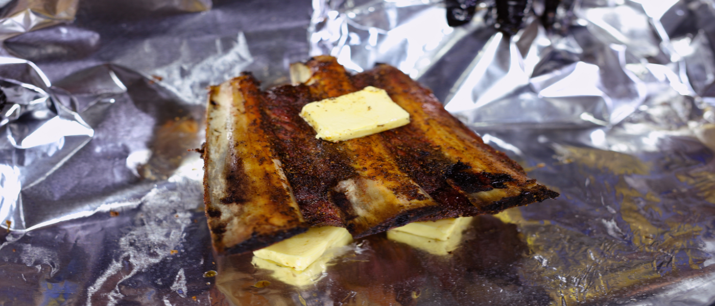 This image shows beef short ribs wrapped in foil with butter